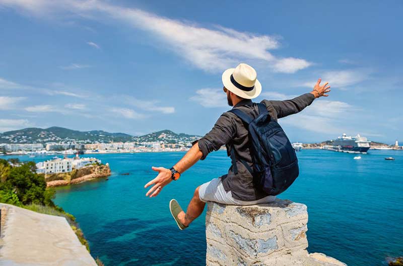 Man poses facing sea at cliff